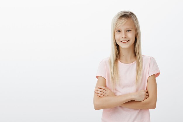 Jeune enfant blond mignon croise la poitrine des bras et souriant heureux