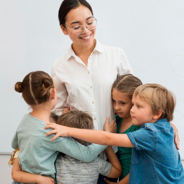 Jeune enseignant étreignant ses élèves