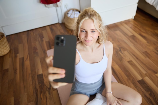 Jeune entraîneur de fitness sportif instructeur de yoga fait une diffusion en direct prend des selfies sur son smartphone pendant