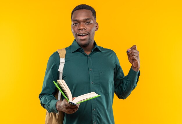 Jeune étudiant afro-américain surpris avec un sac à dos tenant un livre et un stylo