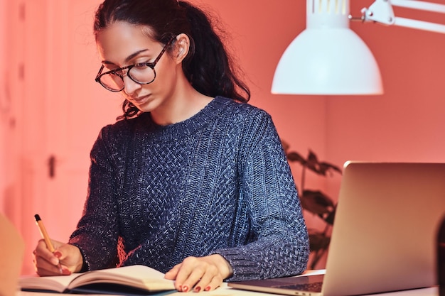 Un jeune étudiant apprend du nouveau matériel assis à côté de la table.