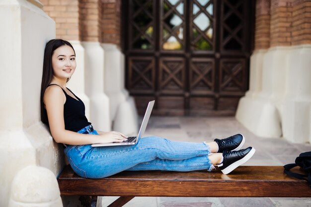 Jeune étudiant asiatique sur le campus universitaire avec ordinateur portable