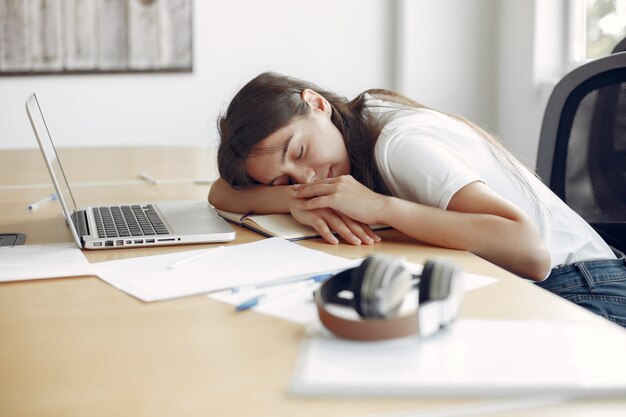 Jeune étudiant assis à la table et dormant