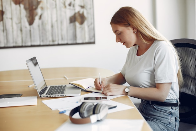 Jeune étudiant assis à la table et utilise son ordinateur portable