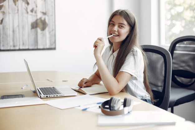 Jeune étudiant assis à la table et utilise son ordinateur portable