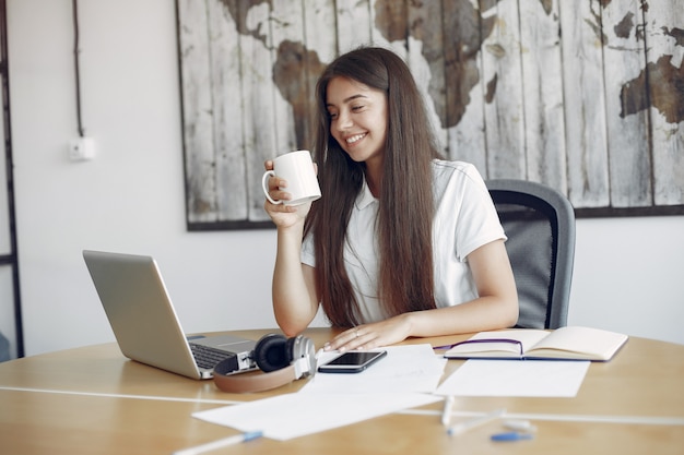 Jeune étudiant assis à la table et utilise son ordinateur portable