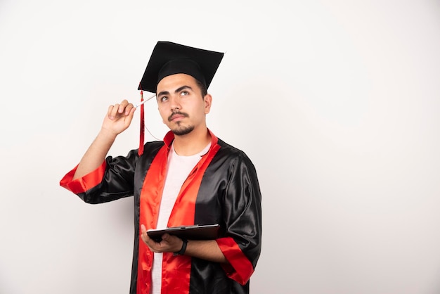 Jeune étudiant diplômé avec diplôme pensant sur blanc.