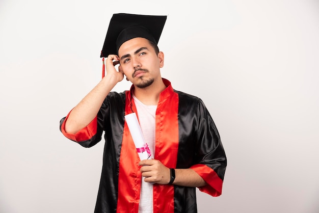 Jeune étudiant avec diplôme pensant sur blanc.