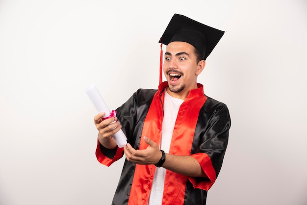 Jeune étudiant diplômé se sentant heureux d'avoir reçu son diplôme sur blanc.