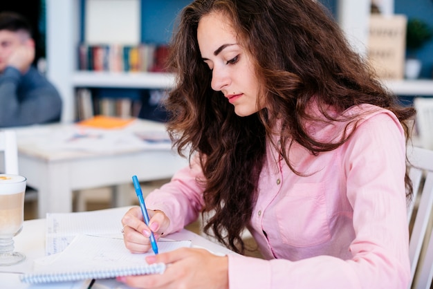 Photo gratuite jeune étudiant écrit dans le cahier