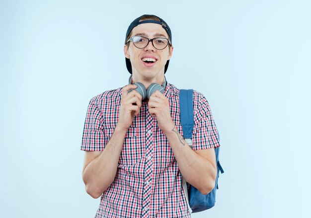 Jeune étudiant garçon portant un sac à dos et des lunettes et une casquette dans les écouteurs sur blanc