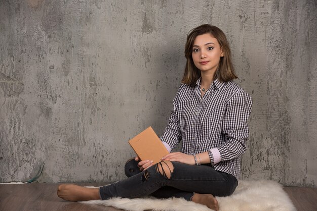 Jeune étudiant posant à l'avant avec un livre orange