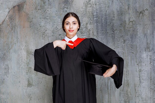 Jeune étudiant en robe posant pour le jour de la remise des diplômes. Photo de haute qualité