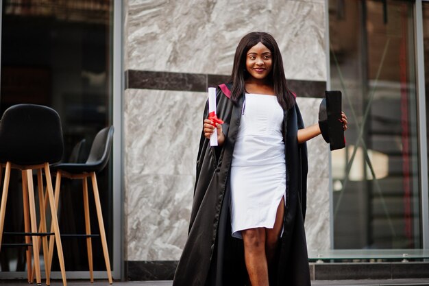 Jeune étudiante afro-américaine avec diplôme pose à l'extérieurxA