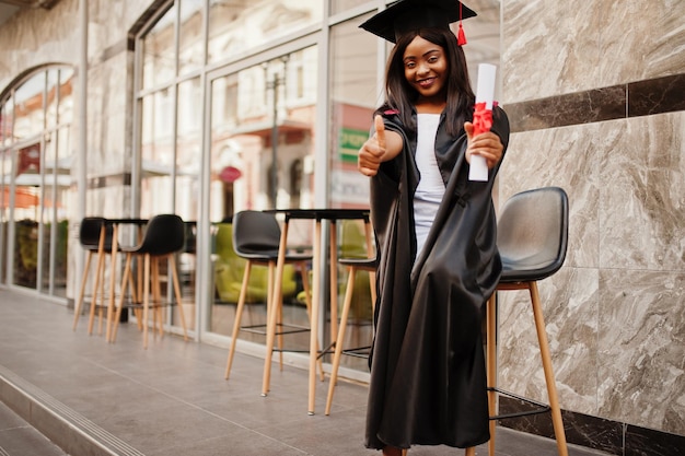 Jeune étudiante afro-américaine avec diplôme pose à l'extérieurxA