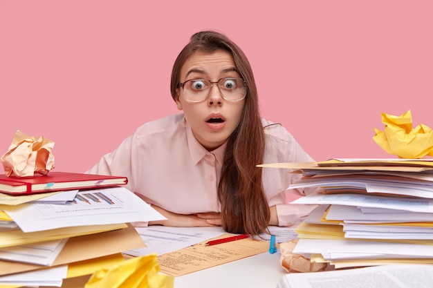 Jeune étudiante brune assise au bureau avec des livres