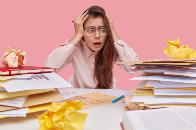 Photo gratuite jeune étudiante brune assise au bureau avec des livres