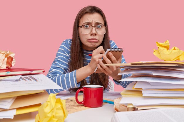 Jeune étudiante brune assise au bureau avec des livres