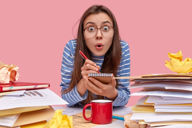 Jeune étudiante brune assise au bureau avec des livres