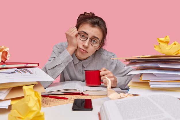 Jeune étudiante brune assise au bureau avec des livres