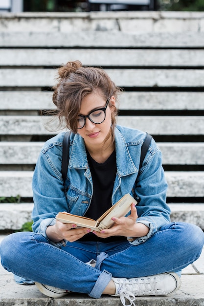 Jeune étudiante, lecture de livre dans les escaliers