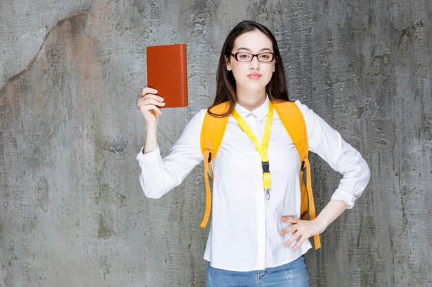 Jeune étudiante à lunettes debout avec livre. Photo de haute qualité