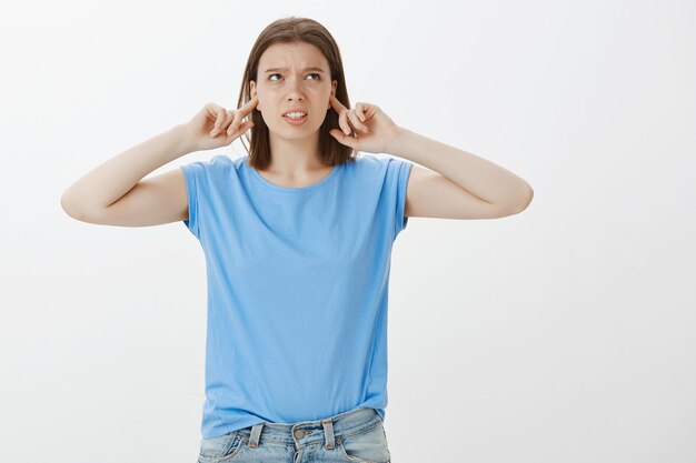 Une jeune étudiante mécontente se plaint de voisins bruyants, ferme les oreilles avec les doigts