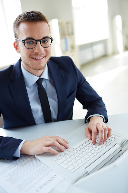 Photo gratuite jeune exécutif avec des lunettes en utilisant le clavier