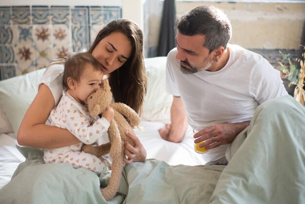 Jeune famille assise dans son lit après s'être réveillé