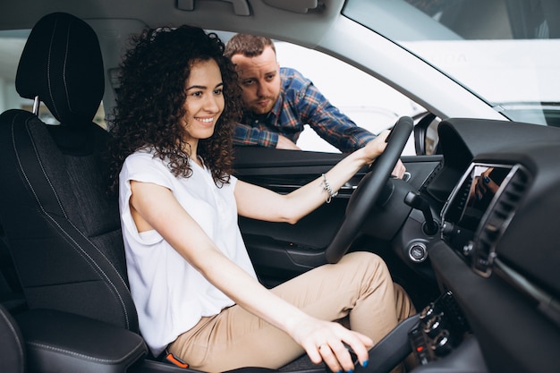 Jeune famille choisissant une voiture dans une salle d'exposition