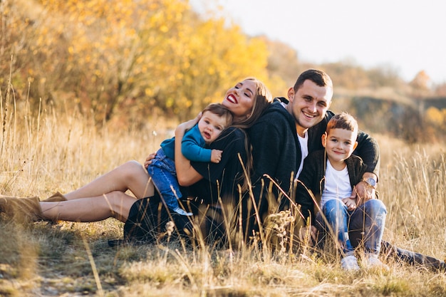 Jeune famille avec deux fils assis ensemble dans le parc