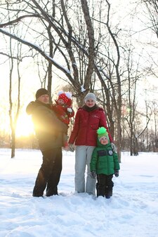 Jeune famille avec enfants en promenade dans le parc en hiver