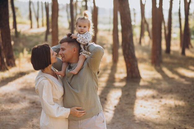 Jeune famille avec jolie petite fille marchant dans la forêt au coucher du soleil