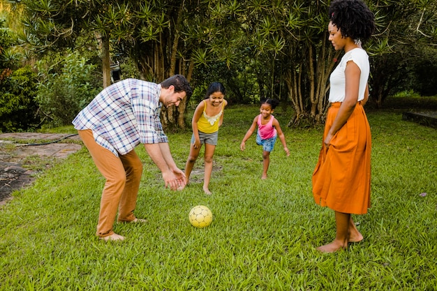 Jeune famille joue au ballon dans le jardin