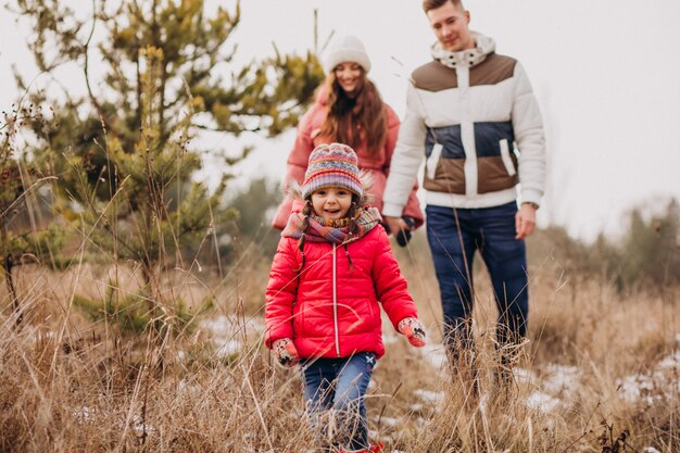 Jeune famille marchant ensemble dans la forêt à l'heure d'hiver