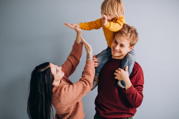 Jeune famille avec petit fils ensemble sur gris