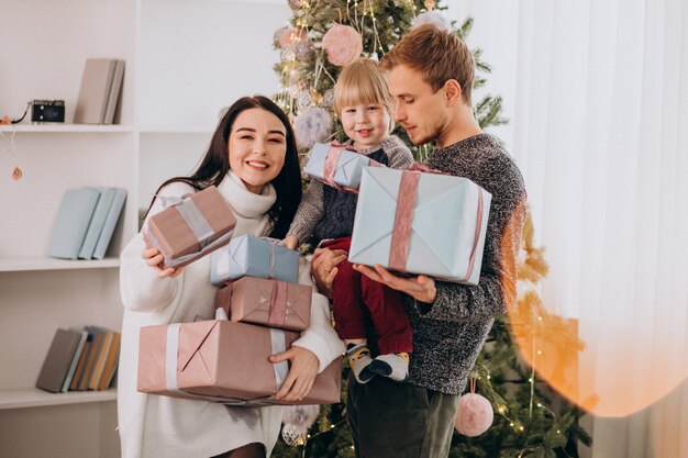 Jeune famille avec petit fils de sapin de Noël tenant des cadeaux de Noël