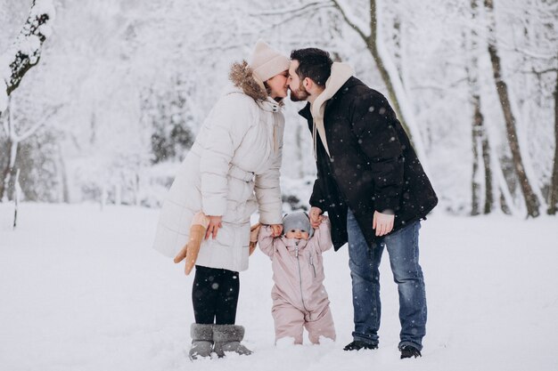 Jeune famille avec petite fille dans une forêt d'hiver pleine de neige