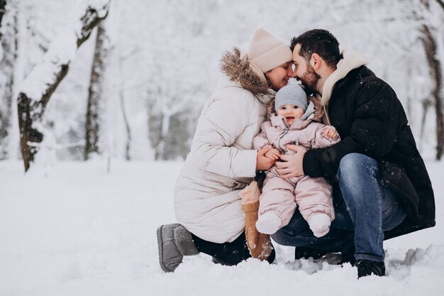 Jeune famille avec petite fille dans une forêt d'hiver pleine de neige