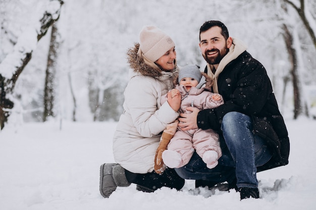 Photo gratuite jeune famille avec petite fille dans une forêt d'hiver pleine de neige