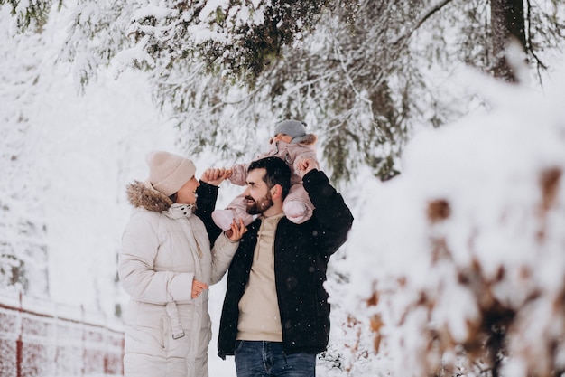 Jeune famille avec petite fille dans une forêt d'hiver pleine de neige