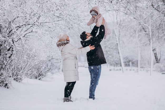 Jeune famille avec petite fille dans une forêt d'hiver pleine de neige