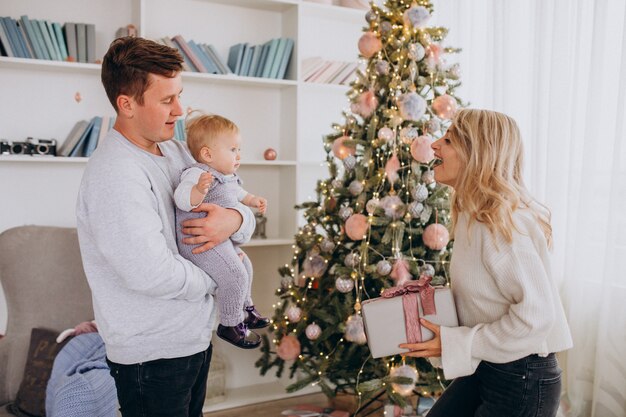 Jeune famille avec petite fille tenant des cadeaux de Noël