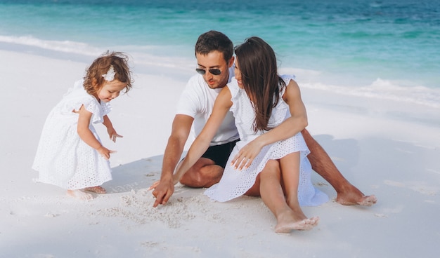 Jeune famille avec petite fille en vacances au bord de l'océan