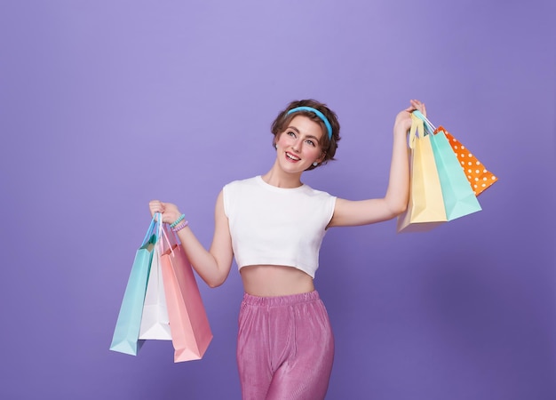 jeune femme acheteuse attrayante portant un sac d'achat isolé sur un fond violet