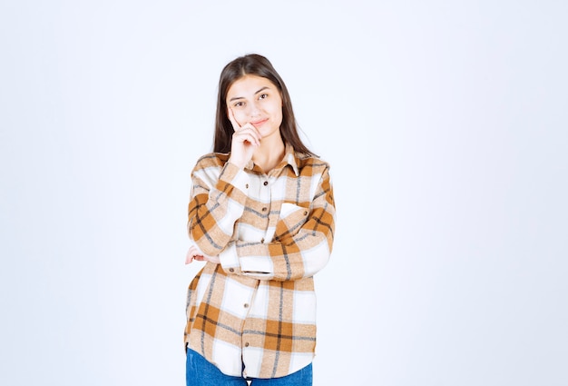 Jeune Femme Adorable Dans Des Vêtements Décontractés, Debout Sur Un Mur Blanc.