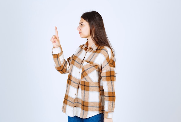 jeune femme adorable debout avec colère sur le mur blanc.