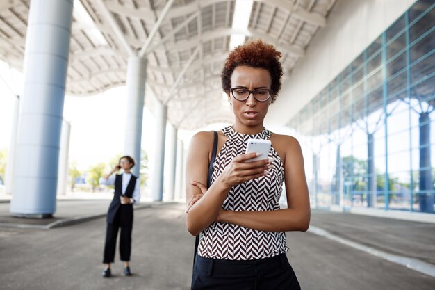 Jeune femme d'affaires africaine réussie regardant téléphone sur centre d'affaires.