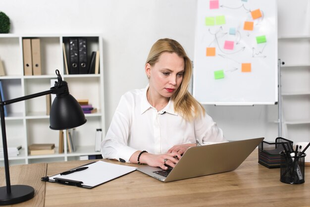 Jeune femme d&#39;affaires à l&#39;aide d&#39;un ordinateur portable au bureau