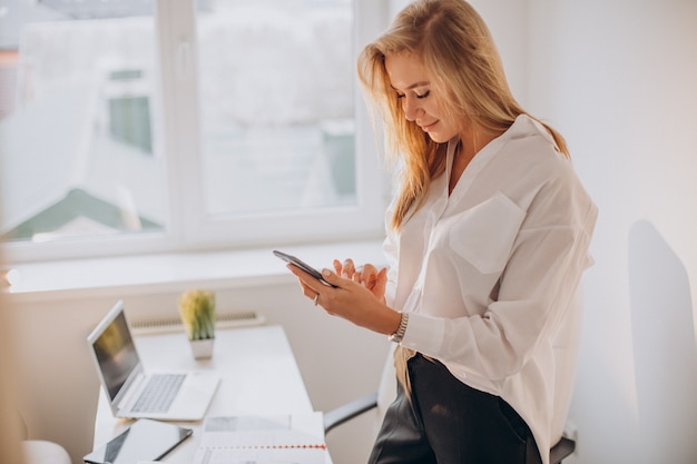 Jeune femme d'affaires à l'aide de téléphone au bureau